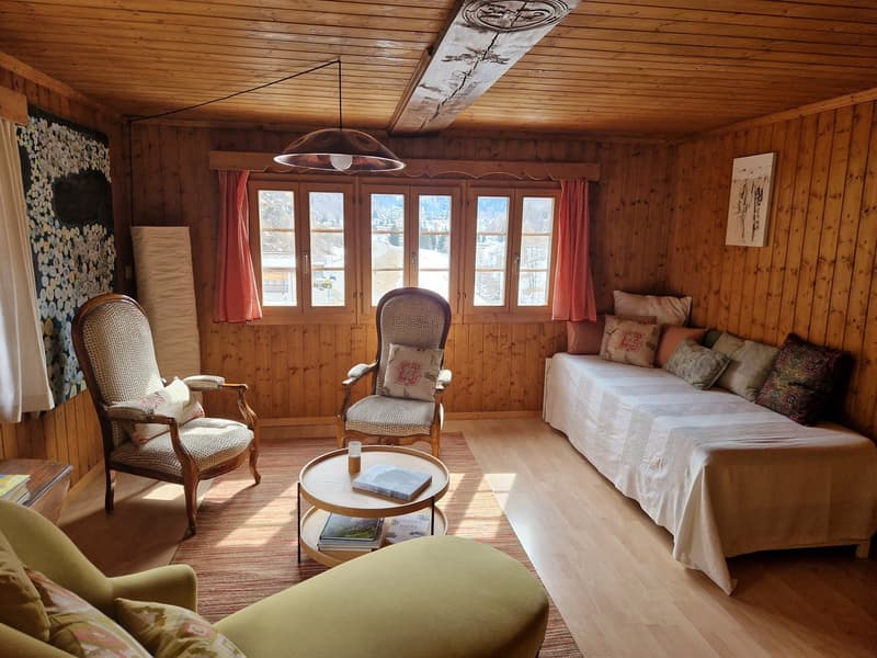 wooden walls, wooden floor, 2 chairs, coffee table, daybed, window with view