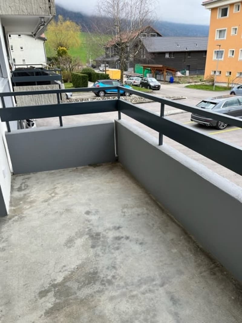 balcony with view, cars parked in lot, 4 story buildings