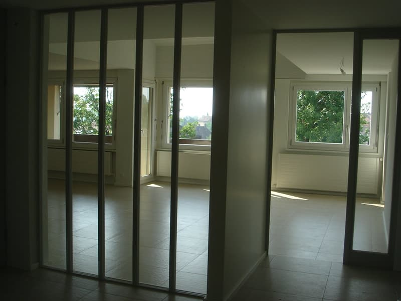 empty room, sliding glass doors, windows, tiled floor, white walls, radiators