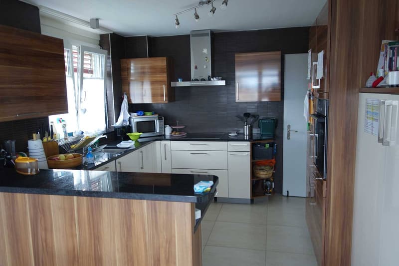 modern kitchen with wooden cabinets, black granite countertops, white appliances, tiled floor, window
