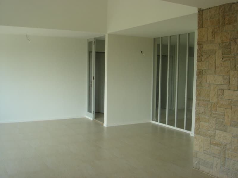 Empty room with white walls, tiled floor, sliding glass doors, and an open door leading to another room.