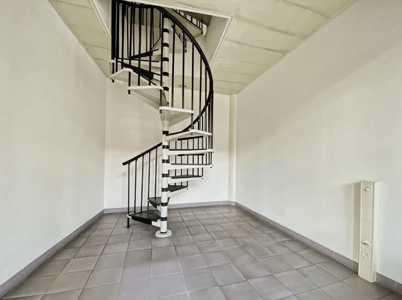 empty room with white walls and spiral staircase