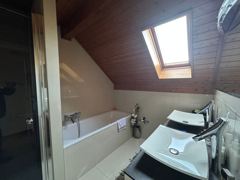 white bathtub, two sinks, wooden ceiling, skylight, white tiles, white towels, flower vase