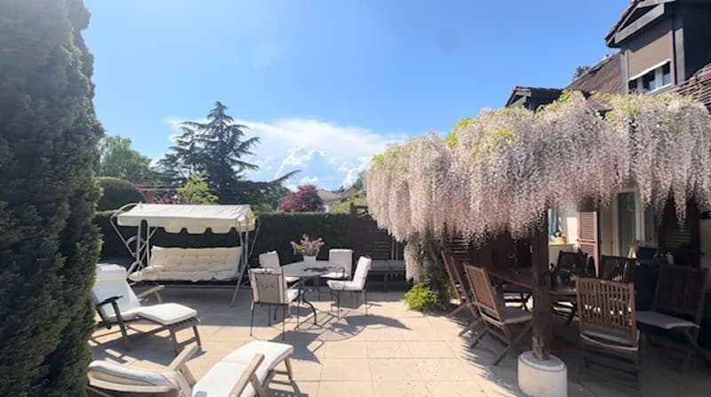 Outdoor seating area with tables and chairs, white canopy, wisteria trees, garden view