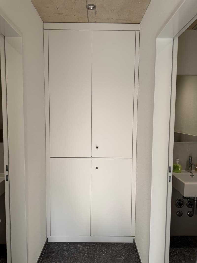 empty room with four built-in white cupboards, dark grey tiled floor, and white walls