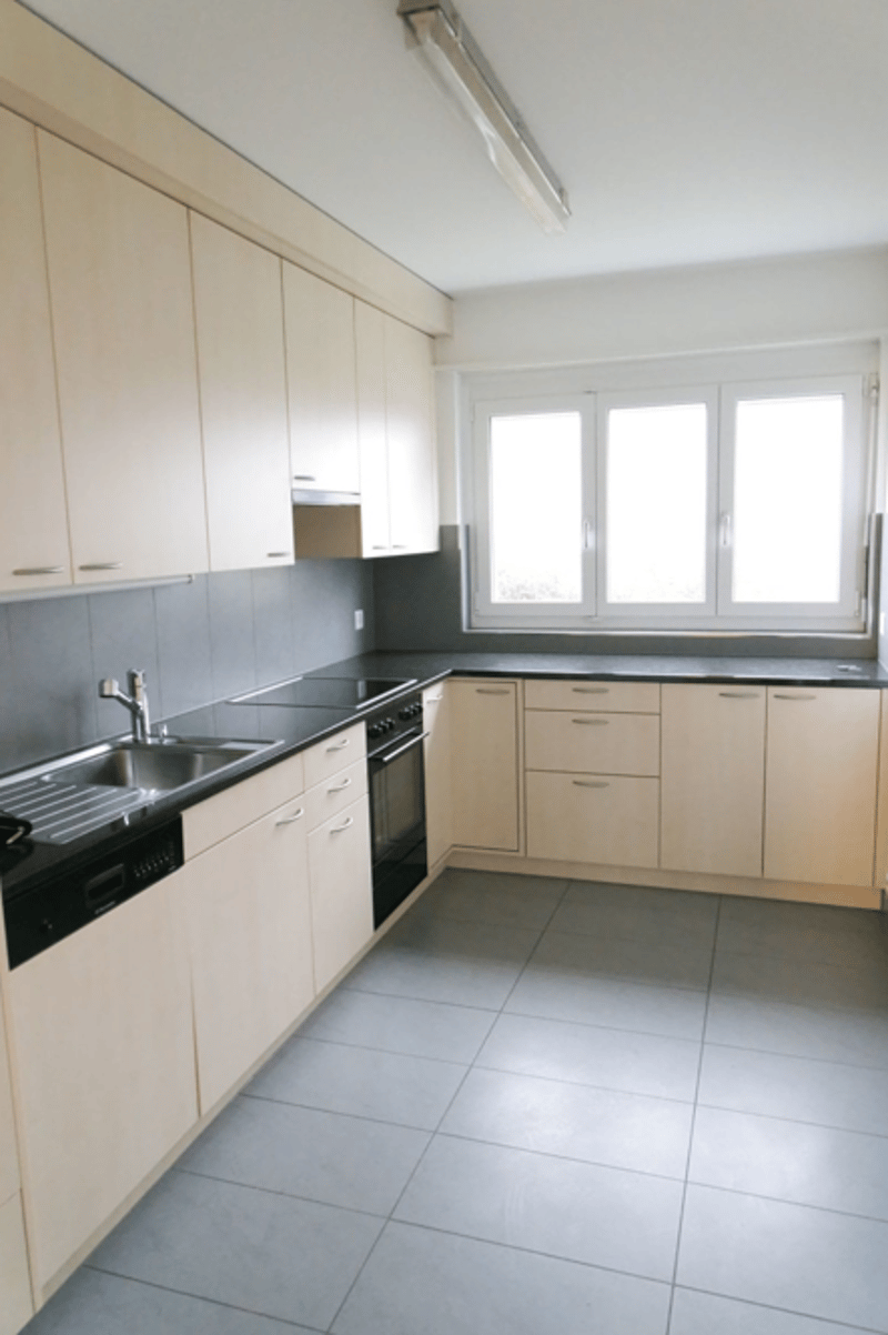 modern kitchen with white cabinets, black countertops, stainless steel sink, dishwasher, gas stove, oven, windows