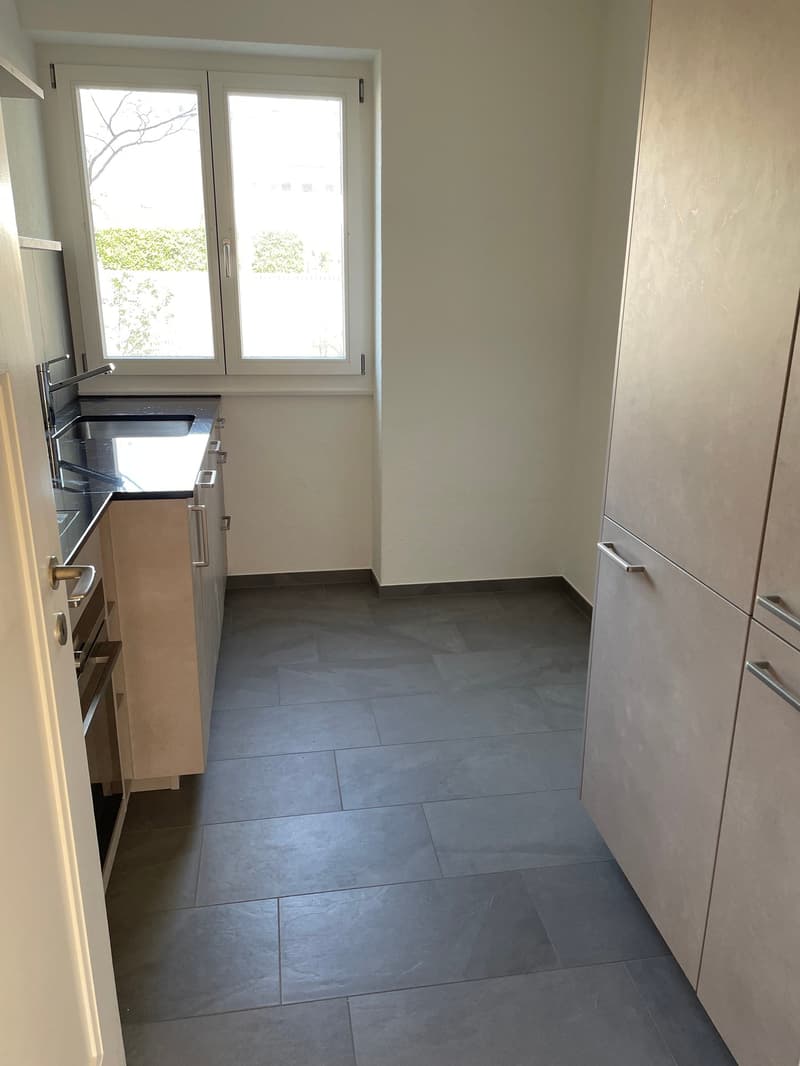 empty kitchen with kitchen island, cabinets, countertop, and sink, window, and tiled floor