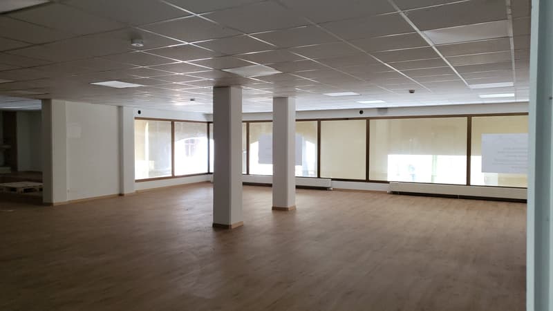 empty room, wooden floors, high ceilings, several large windows, two central pillars
