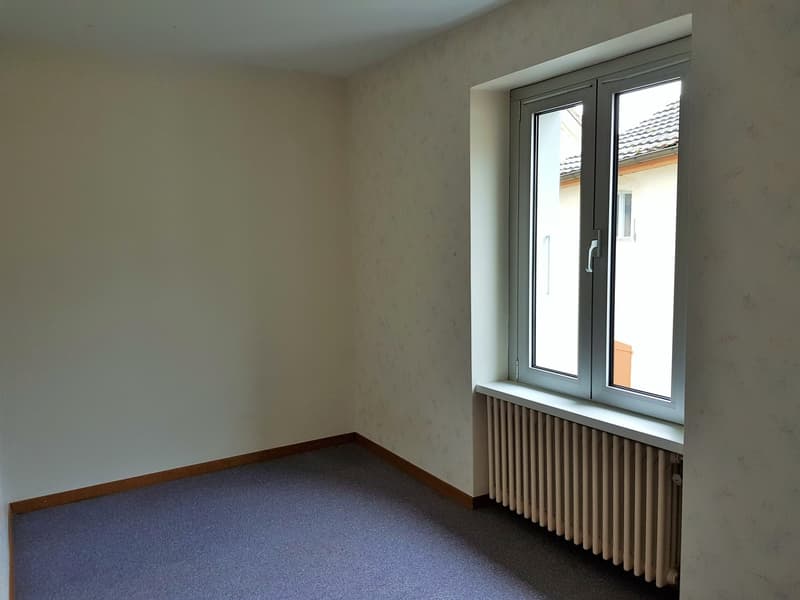 empty room with white walls, blue carpet, window with white frame, white radiator