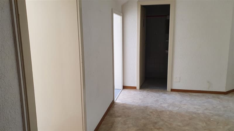 An empty hallway leading to a bathroom and an unknown room