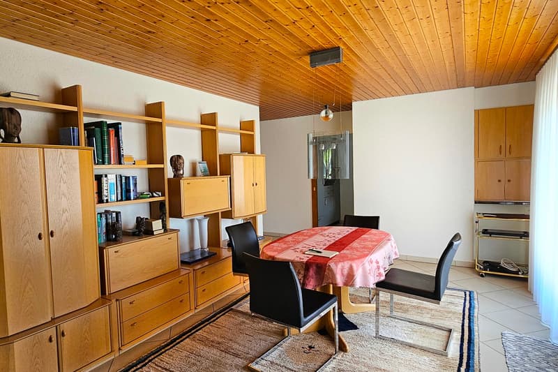 Dining area with a round table and chairs, wooden cabinets, a rug, and wooden ceiling