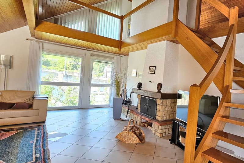 fireplace, rug, sofa, large window with view, stairs to the upper floor