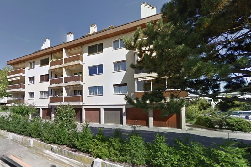3 story building, white painted exterior, brown wood trim, balconies on each floor, underground garage