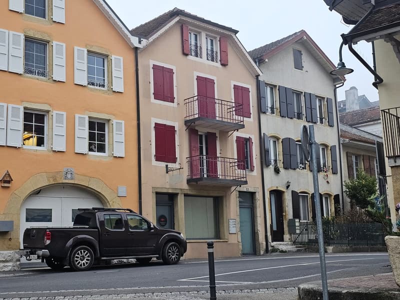 Three story building, multiple windows, balcony, red shutters