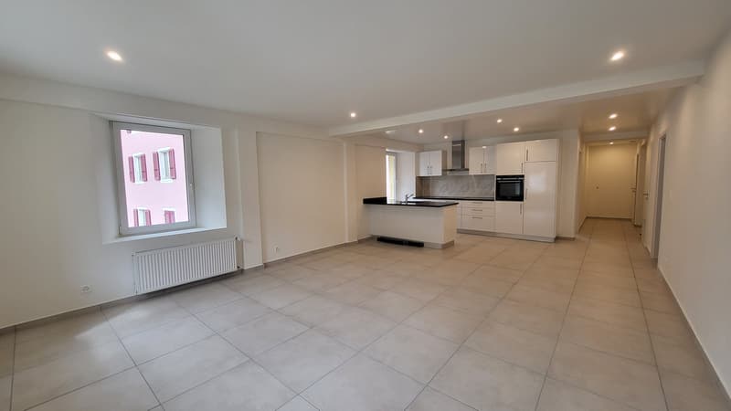 Open plan kitchen and living room, modern design, white cabinets, tiled floor, large window, kitchen island, modern appliances
