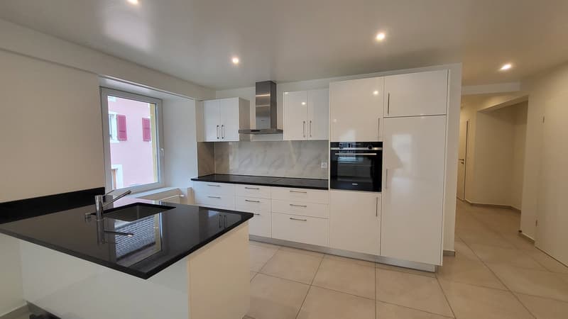 modern kitchen with white cabinets, black countertops, integrated dishwasher, oven, and stove