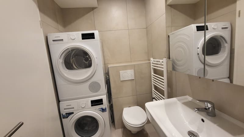 Small bathroom with toilet, sink, washing machine, and dryer