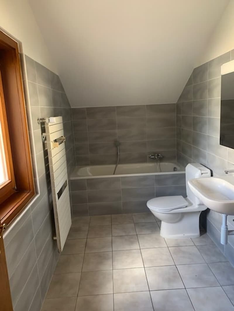 Bathroom with bathtub, sink, toilet, white and gray tiles, and window