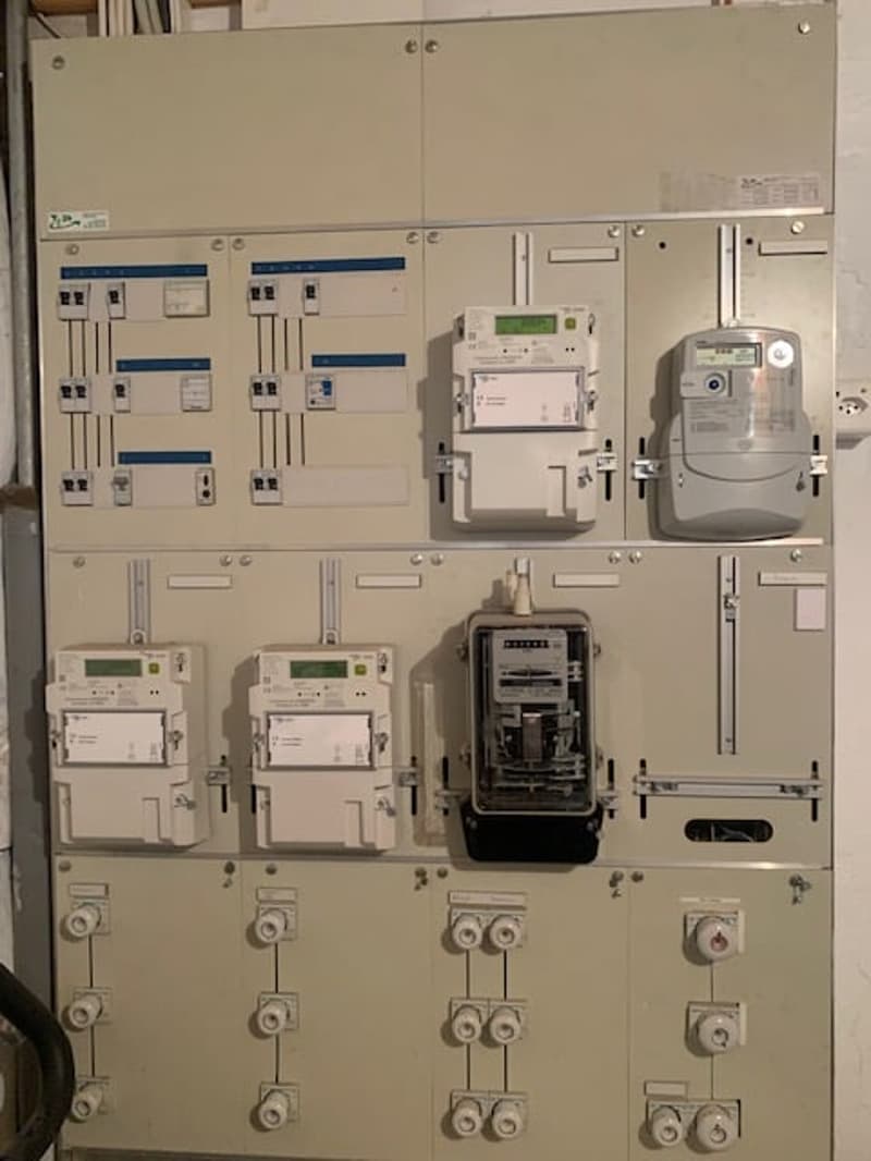 The image shows an electrical panel with various circuit breakers, meters, and other electrical equipment. The panel appears to be used for power distribution and monitoring in a building or facility.