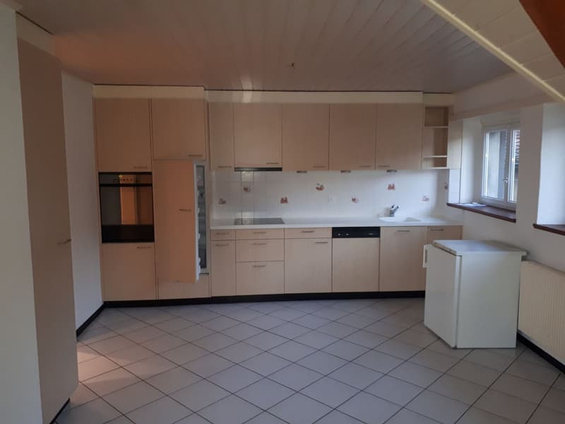 Spacious kitchen with beige cabinets, tiled floor, and built-in appliances including a dishwasher