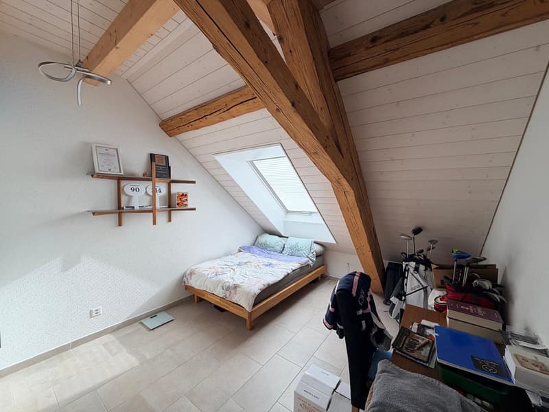wooden ceiling beams, bed, storage shelves, golf equipment, books, electrical outlets, windows