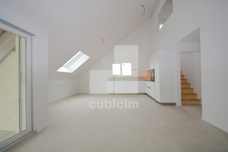 Open-concept living space with vaulted ceiling, skylights, white walls, hardwood floors, and a modern kitchen with built-in appliances including a dishwasher.