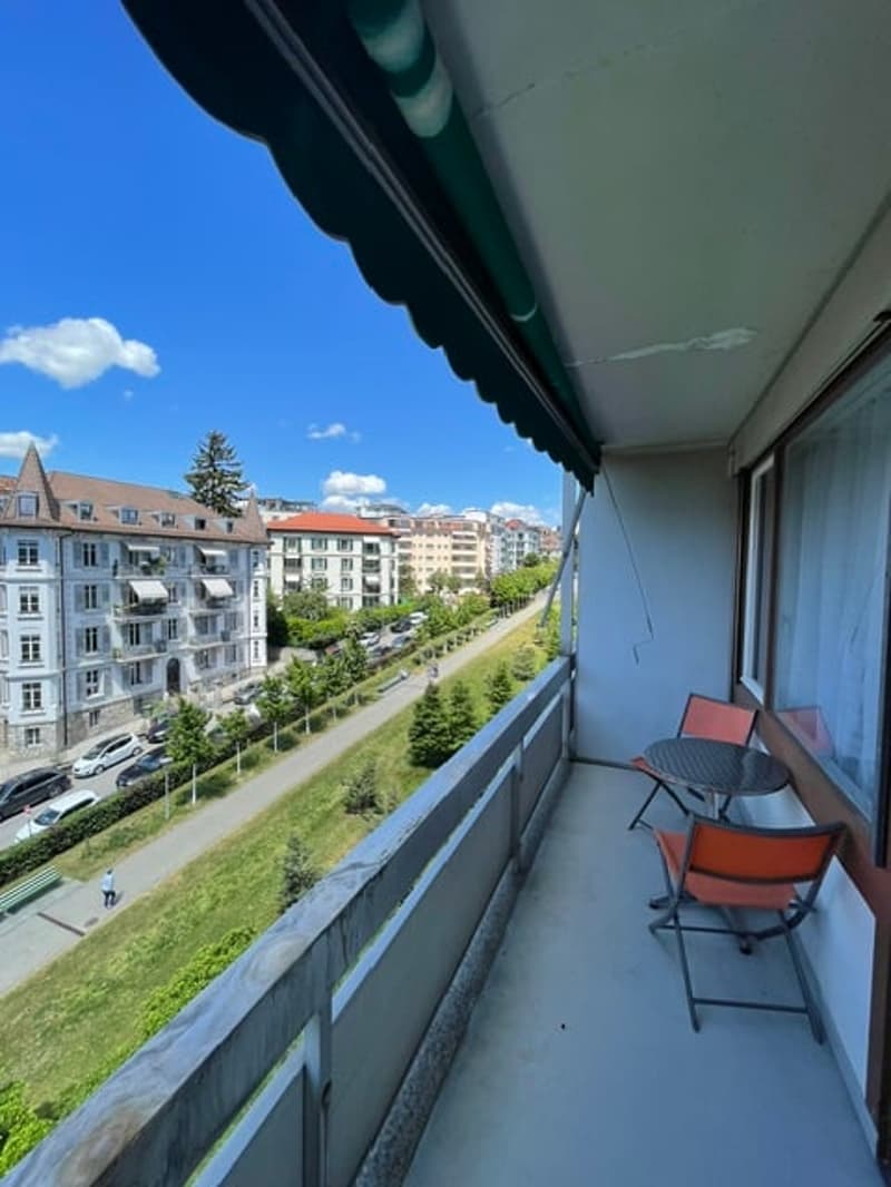 Balcony / Terrace. Balcony with outdoor furniture, overlooking a cityscape with buildings and greenery.