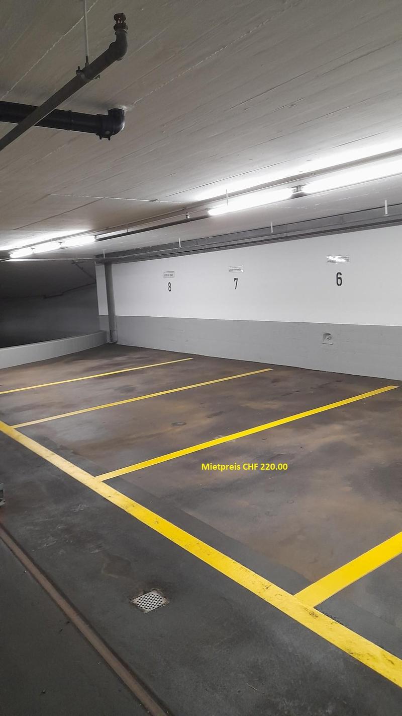 Empty parking lot with yellow lines, white walls, and ceiling lights