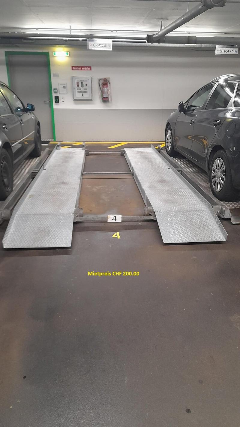 underground parking lot, two cars parked, two ramps, yellow lines, fire extinguisher