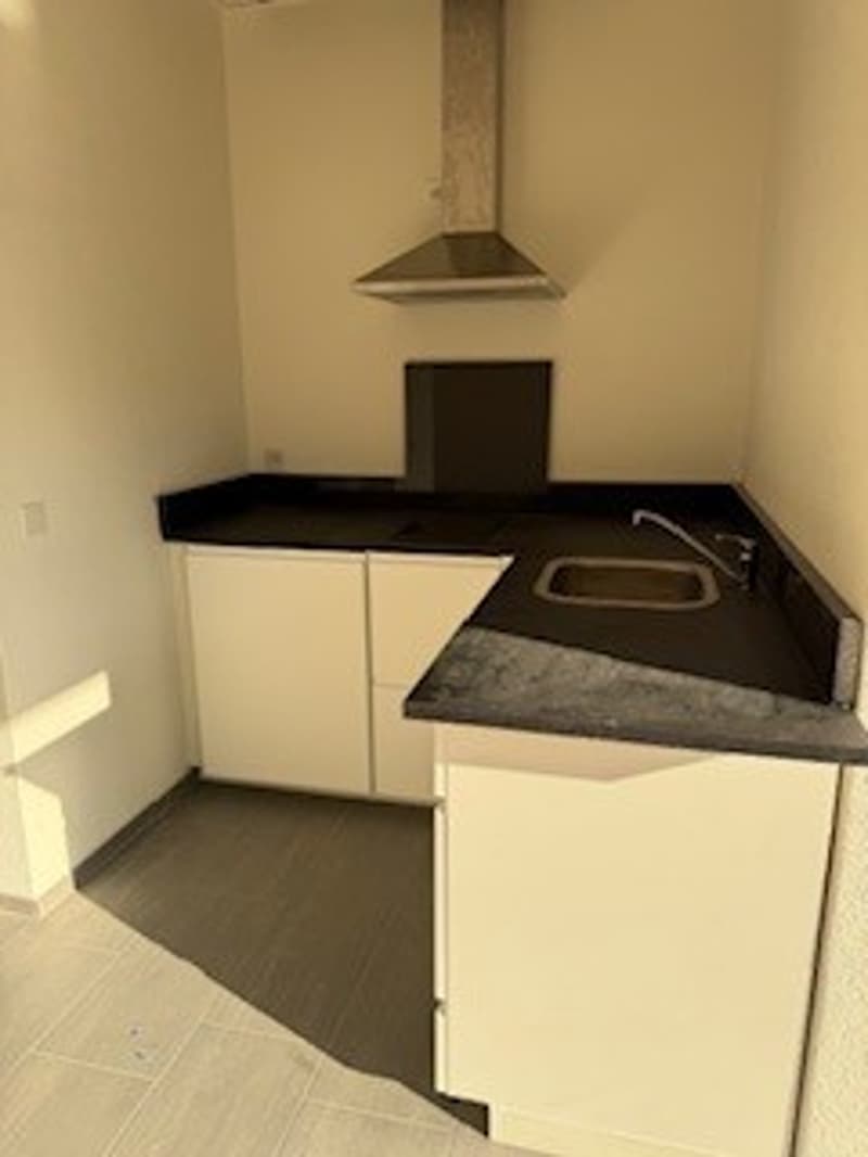 Modern kitchen, white cabinets, black countertops, kitchen hood, stainless steel sink, faucet, tiled floor