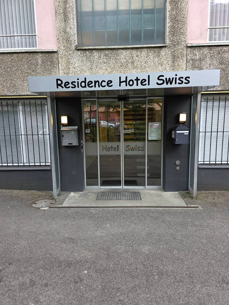 Entrance to Residence Hotel Swiss with glass doors, signage, and mailboxes on either side.