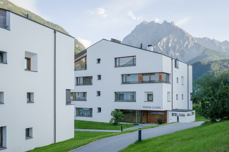modern 3 story building, white exterior, wooden windows, entrance on the bottom floor, mountain view