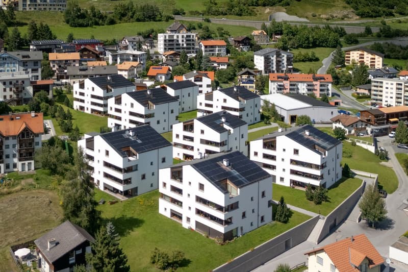 Collection of multi-storey buildings, modern design, solar panels on roofs, surrounded by greenery