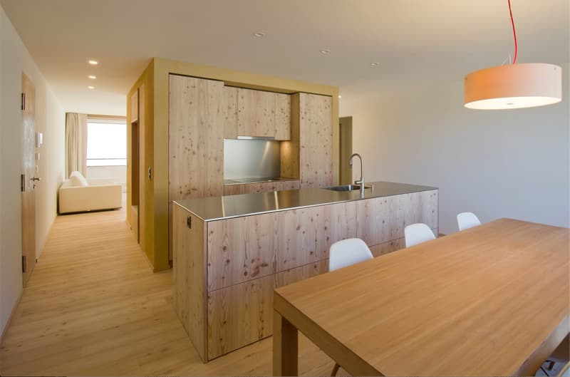 modern kitchen with dining table, wooden cabinets, stainless steel countertop, wooden floor, large windows