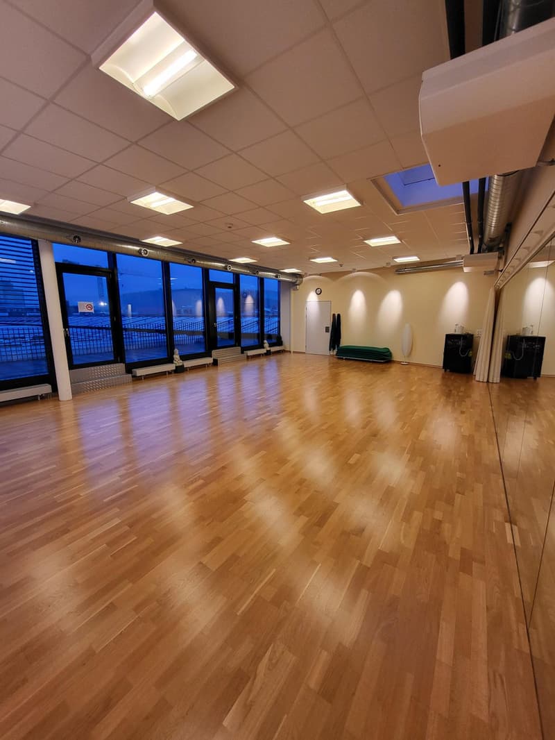 Spacious room with hardwood floors, large windows, modern lighting, and a view to the outside