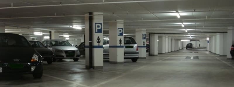 Parking garage with white columns, underground, numbered parking spots, cars parked
