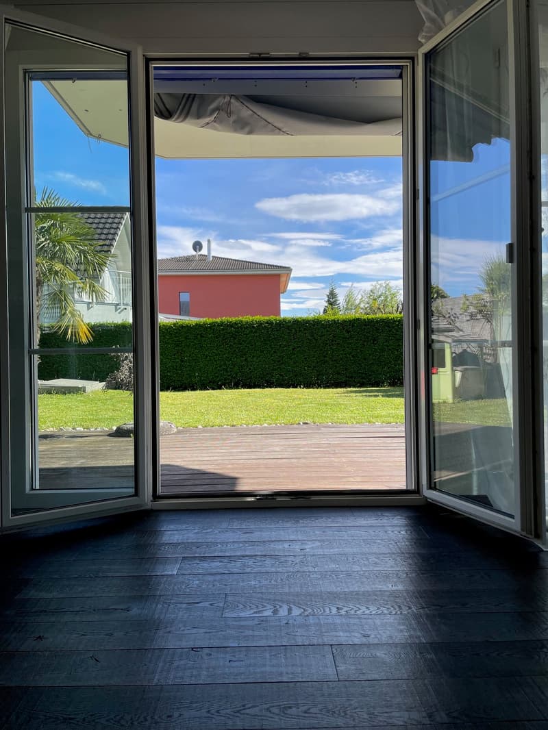 Blick vom Wohnzimmer in den Garten und die gedeckte Terrasse