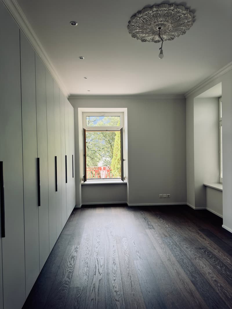 Empty room, wooden floor, built-in closets, large window with a view of trees