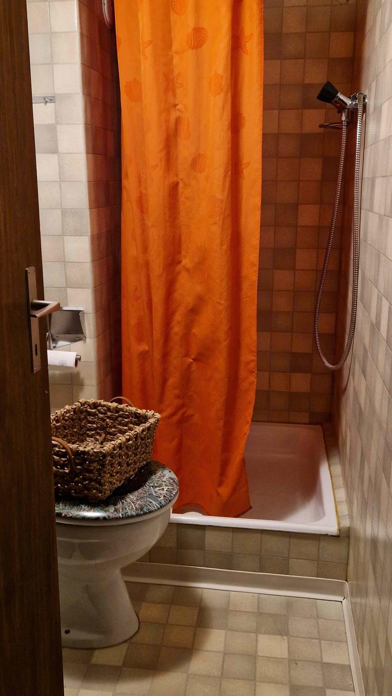 tiled walls, shower area, bathtub, toilet, storage basket, curtain