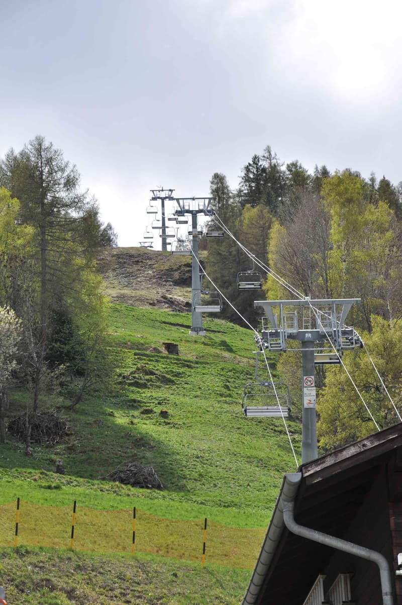House at the bottom of the ski lift, with ski lift towers on the hill