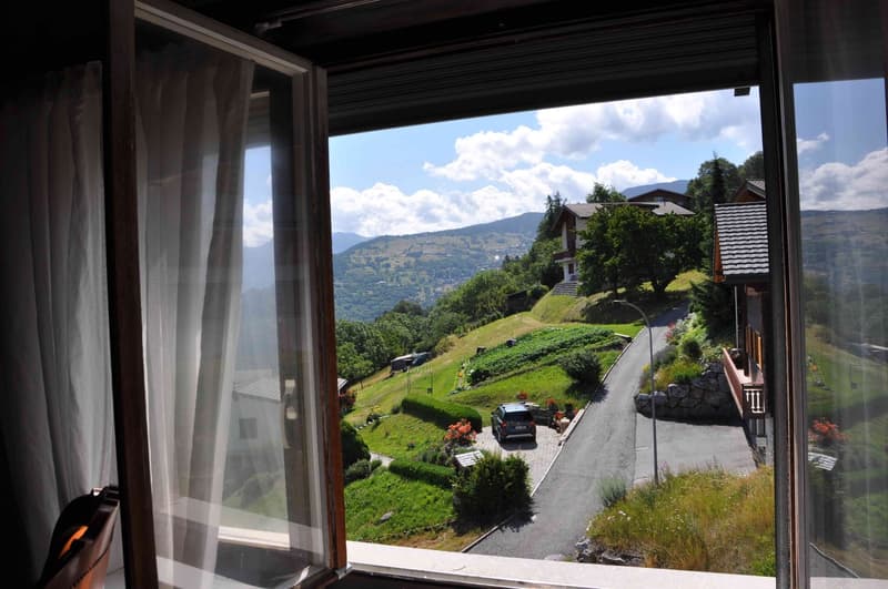View of slope, car, mountain range, greenery, house, road, grass, street light, flowers