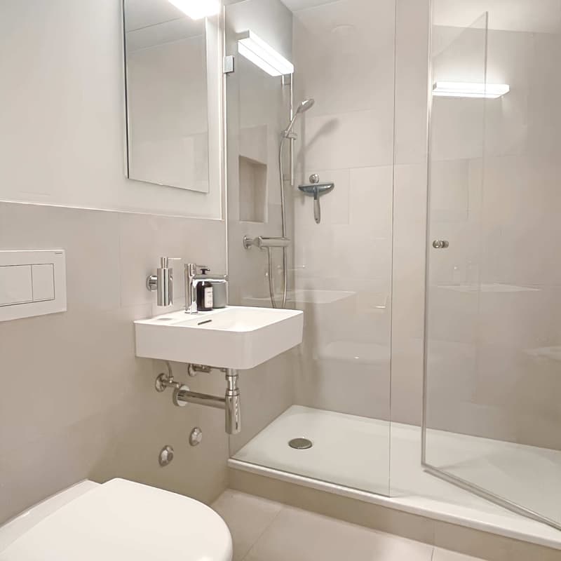 modern bathroom with white tiles, glass shower, sink with faucet, and mirror