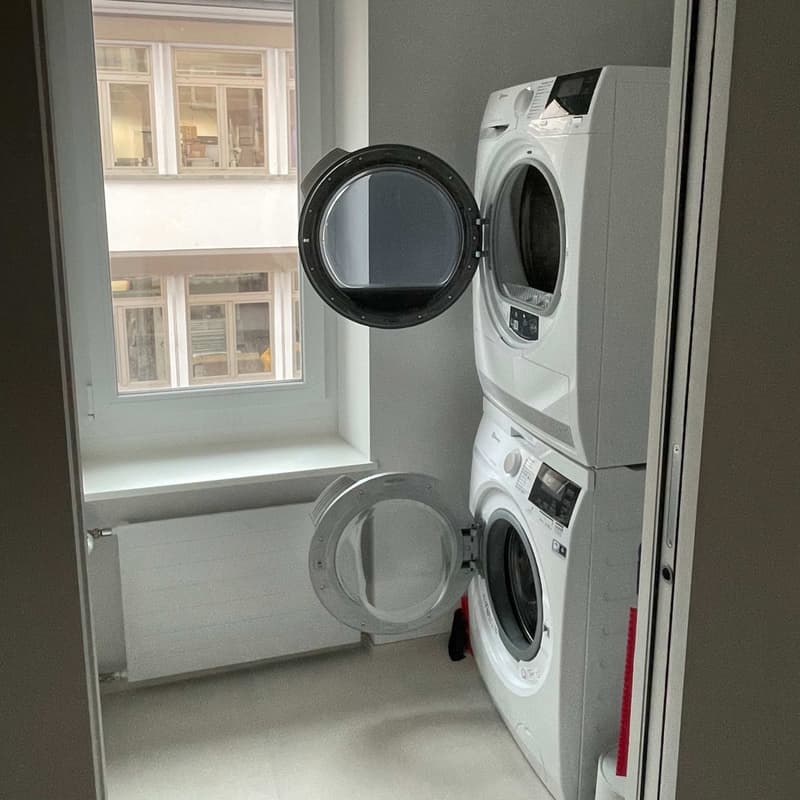Washer-dryer machines stacked one above the other, window, radiator
