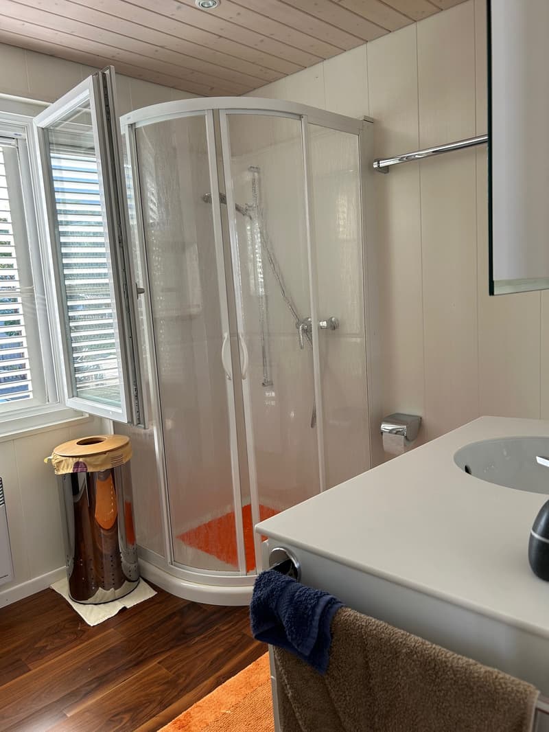 small bathroom with shower, sink, and a small window with blinds