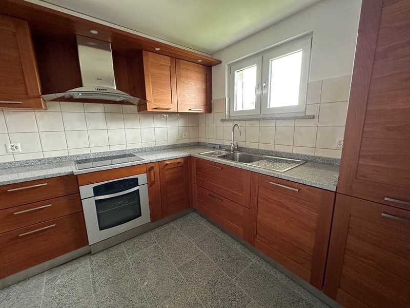 Spacious L-shaped kitchen with wooden cabinets, granite countertops, stainless steel appliances including a dishwasher, and tiled flooring.