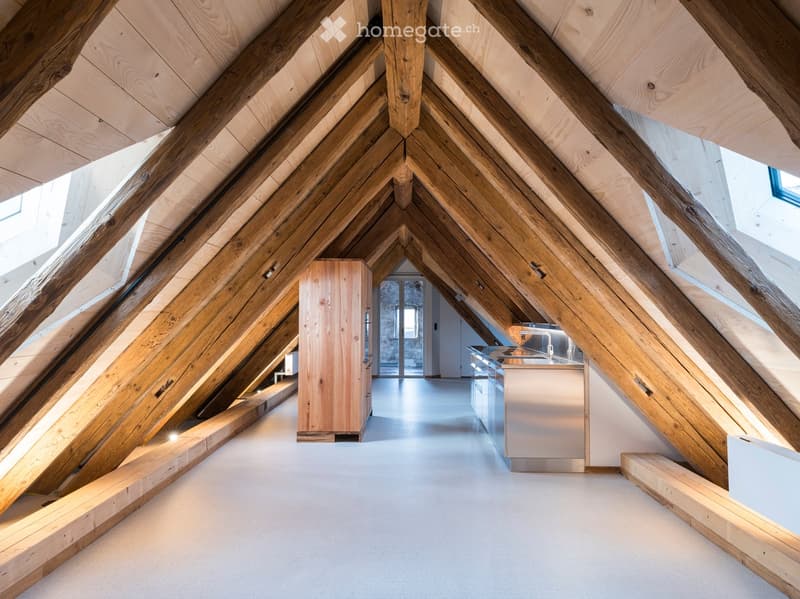 Triangular space, wooden beams, white floors, kitchen with white appliances, skylights