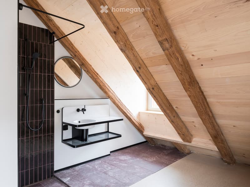 small bathroom with wooden beams, mirror, sink, and black tiled wall