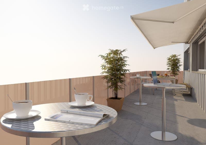 Outdoor balcony or terrace with round tables, chairs, potted plants, and a large umbrella providing shade