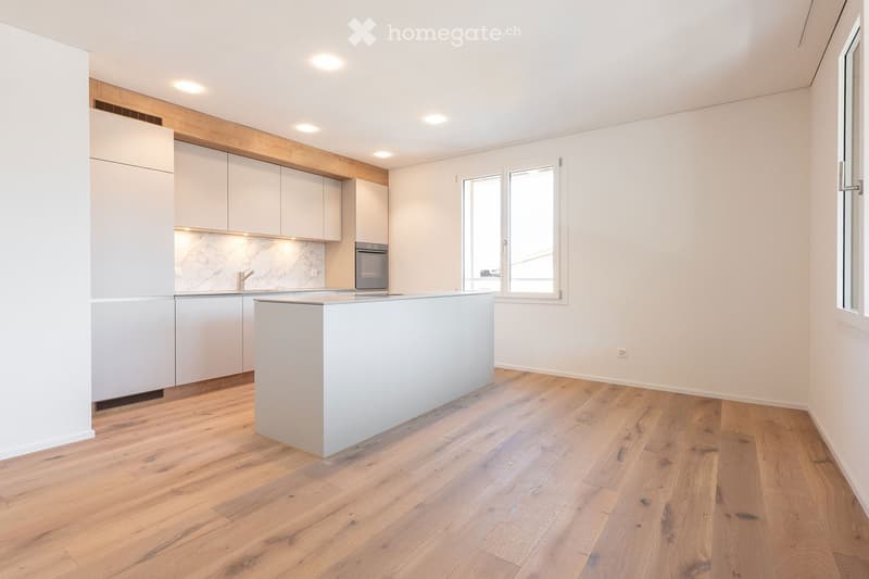 Modern kitchen with light-colored cabinets, a central island, and wooden flooring.