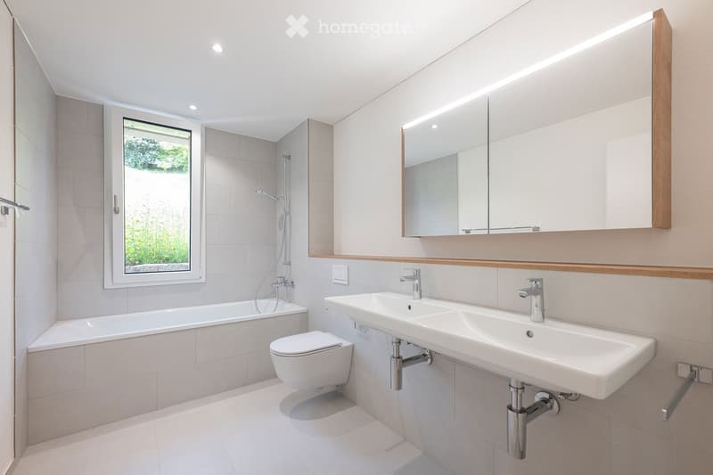 modern bathroom with bathtub, toilet, double sink, mirror, and shower